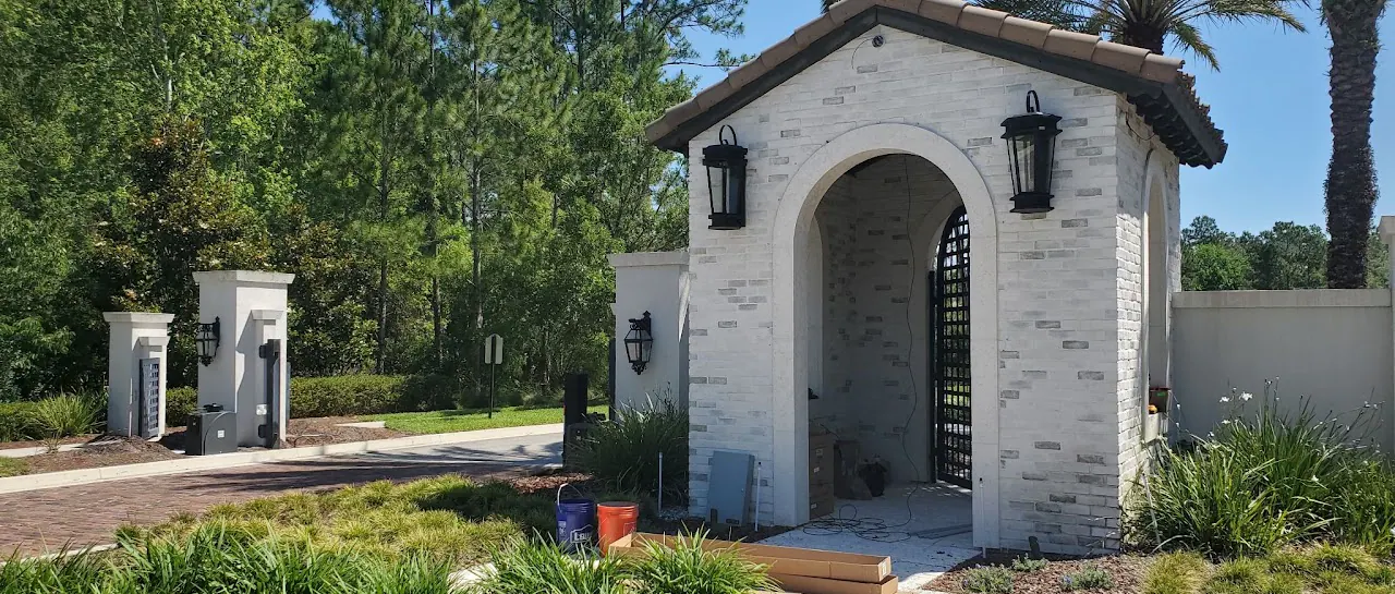 Stone archway entrance with lanterns and an iron gate, no people
