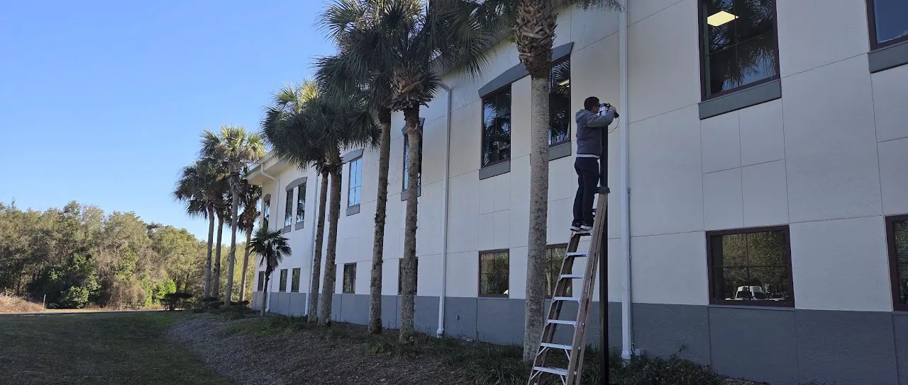 Technician on a ladder at the wall of a two-story building