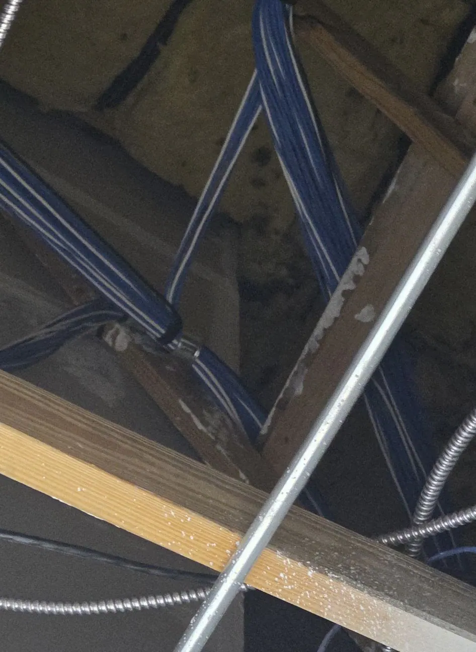 Blue cables routed through a ceiling space along metal conduit