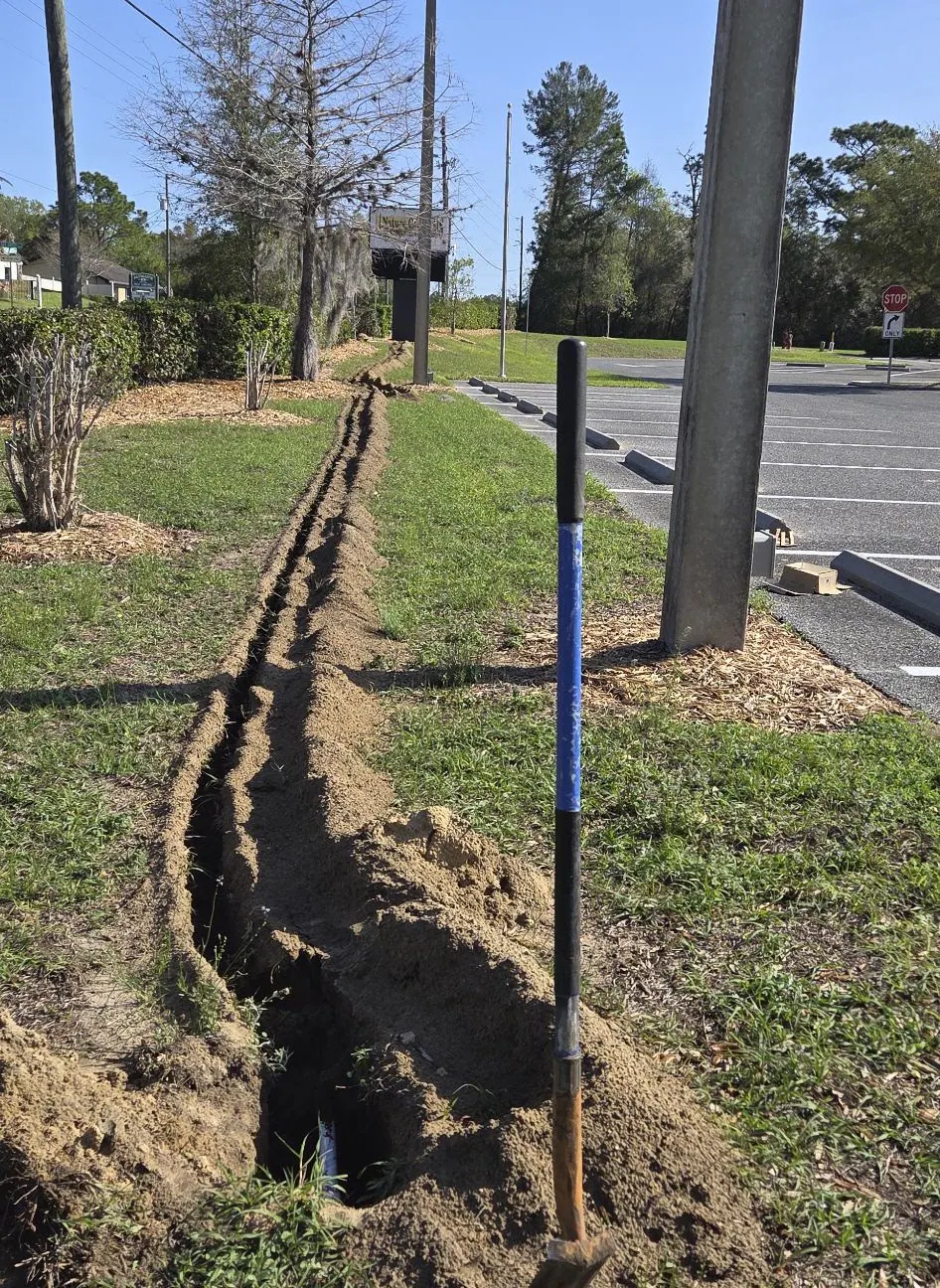Open trench for underground conduit beside a parking lot