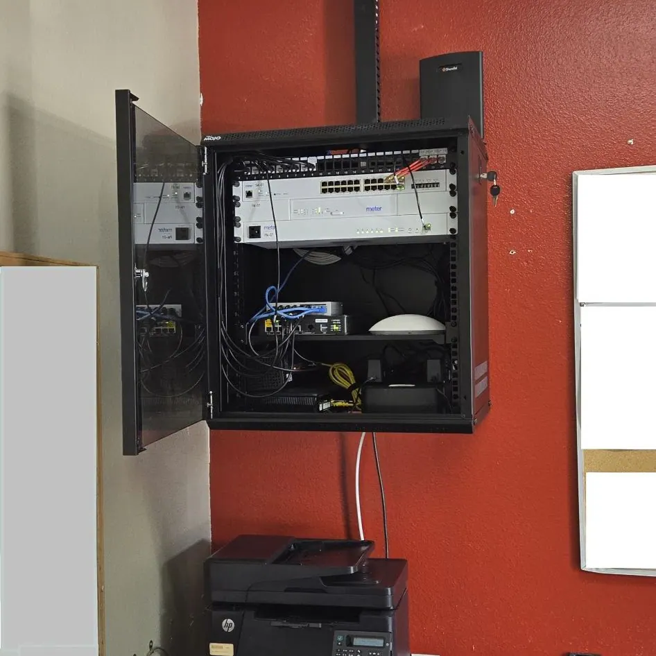Open wall cabinet with switches and wireless gear on a red wall