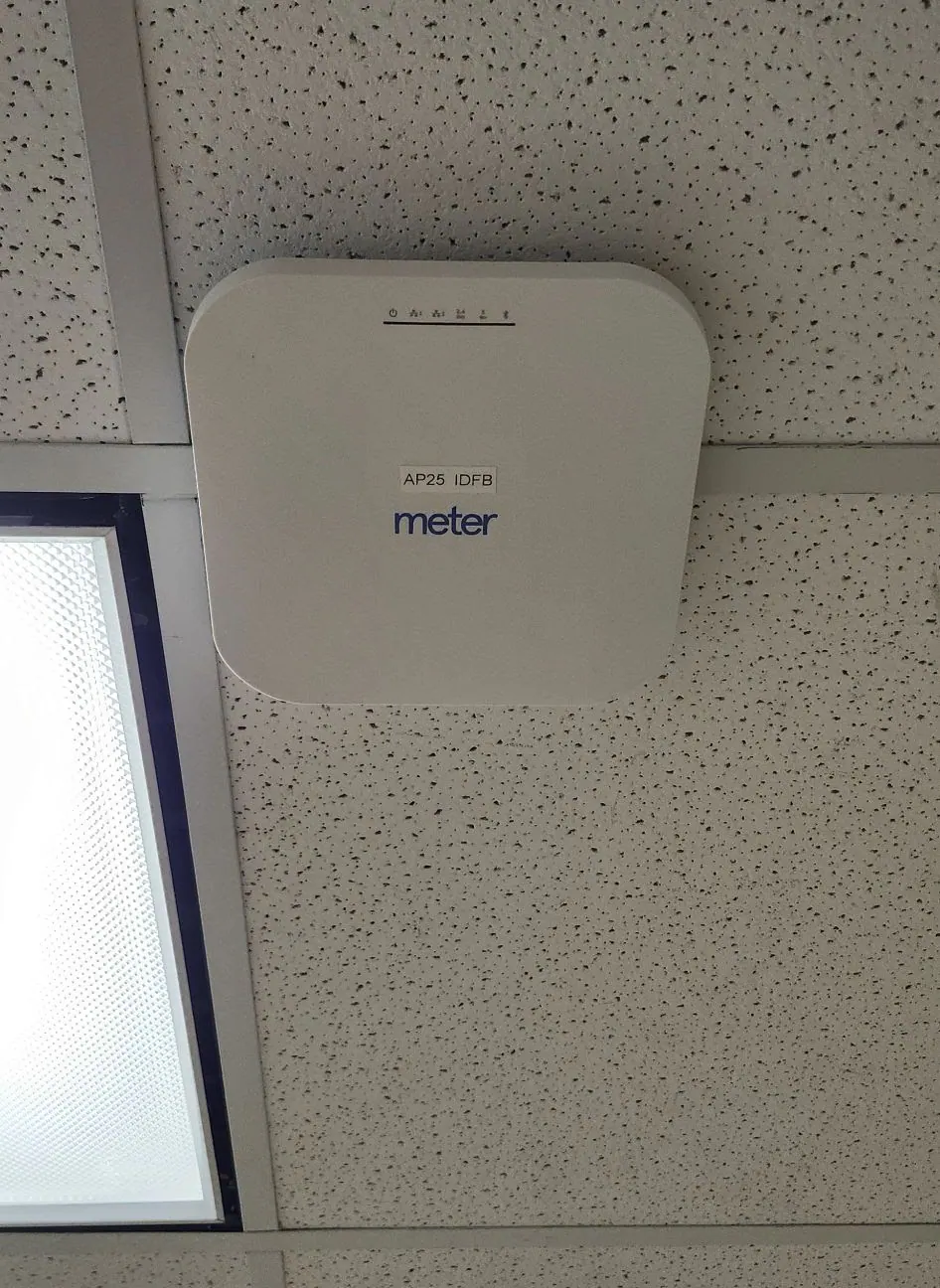 White ceiling-mounted wireless access point above a light panel