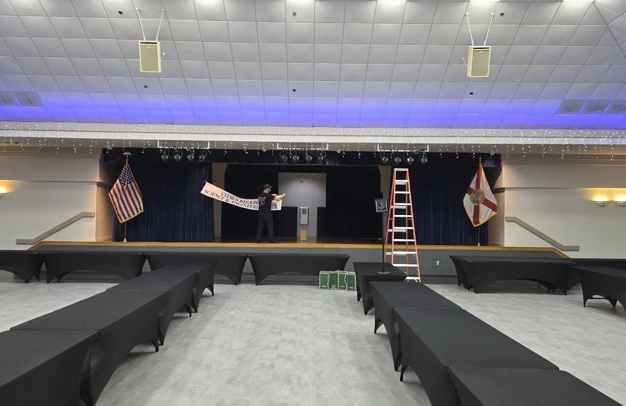 Hall with blue ceiling cove light, black drapes and a stage