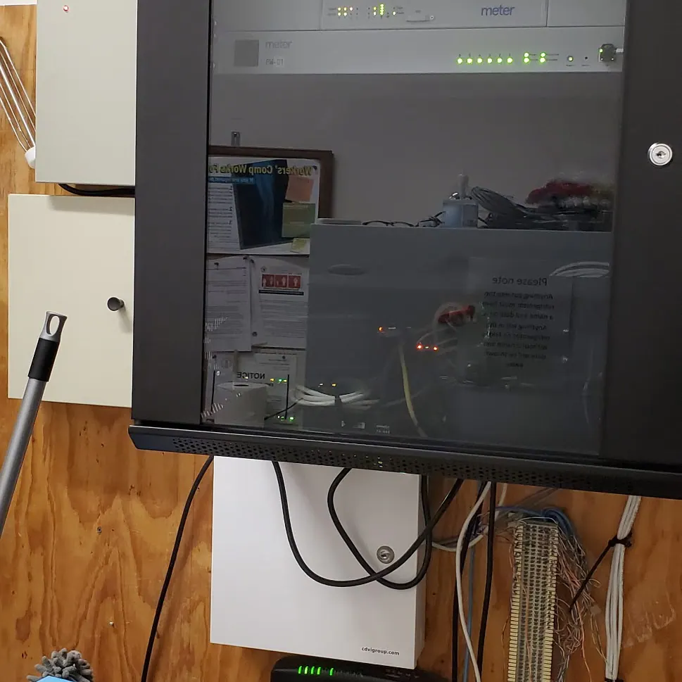 Dark monitor mounted on a wood-panelled wall above cabling