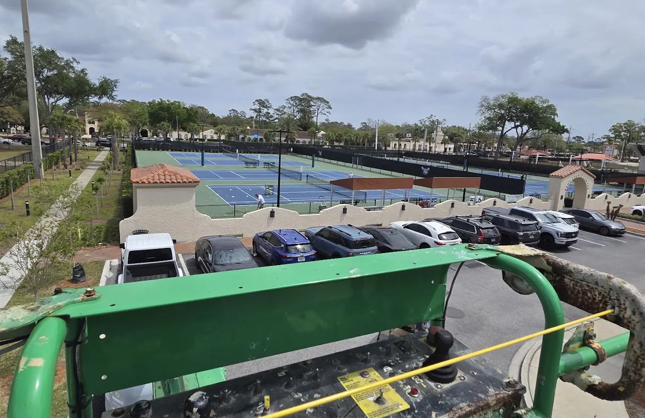 Elevated view of tennis courts, parking lot and Spanish-style roofs