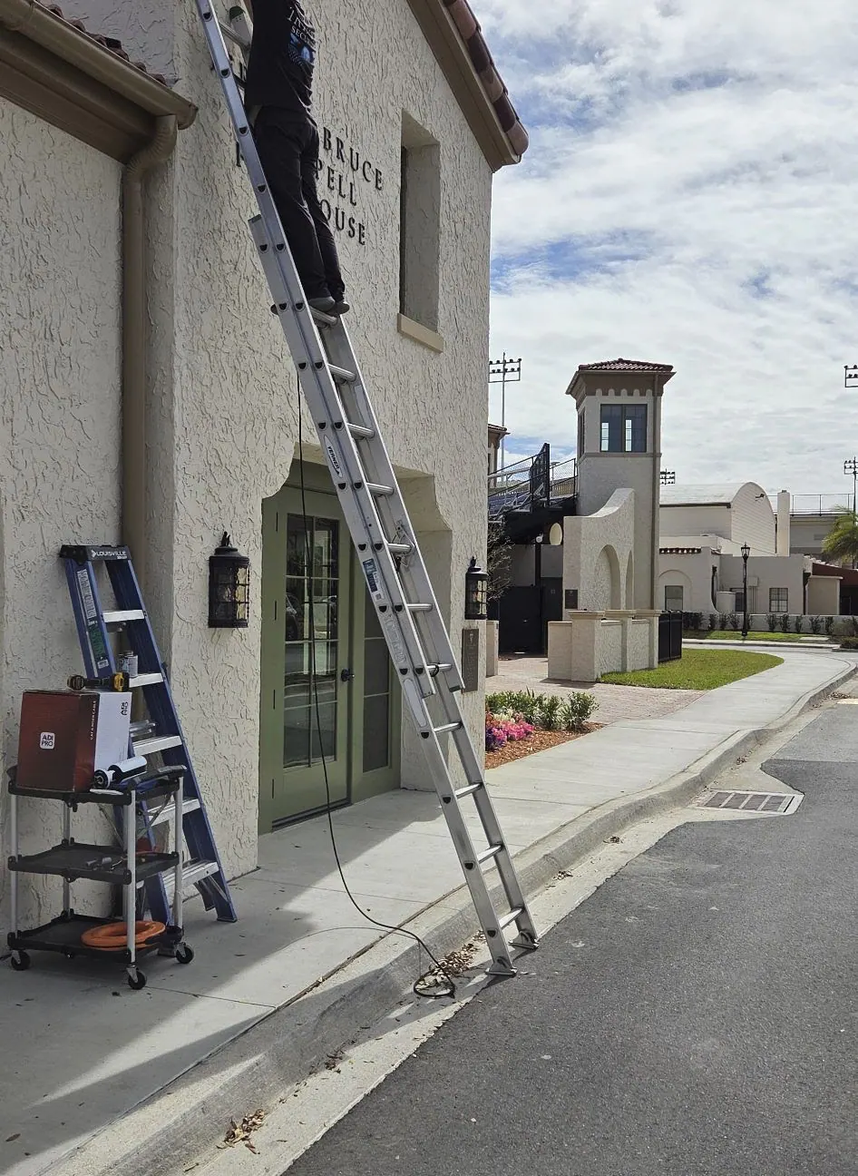 Ladders against a cream stucco building with a green door