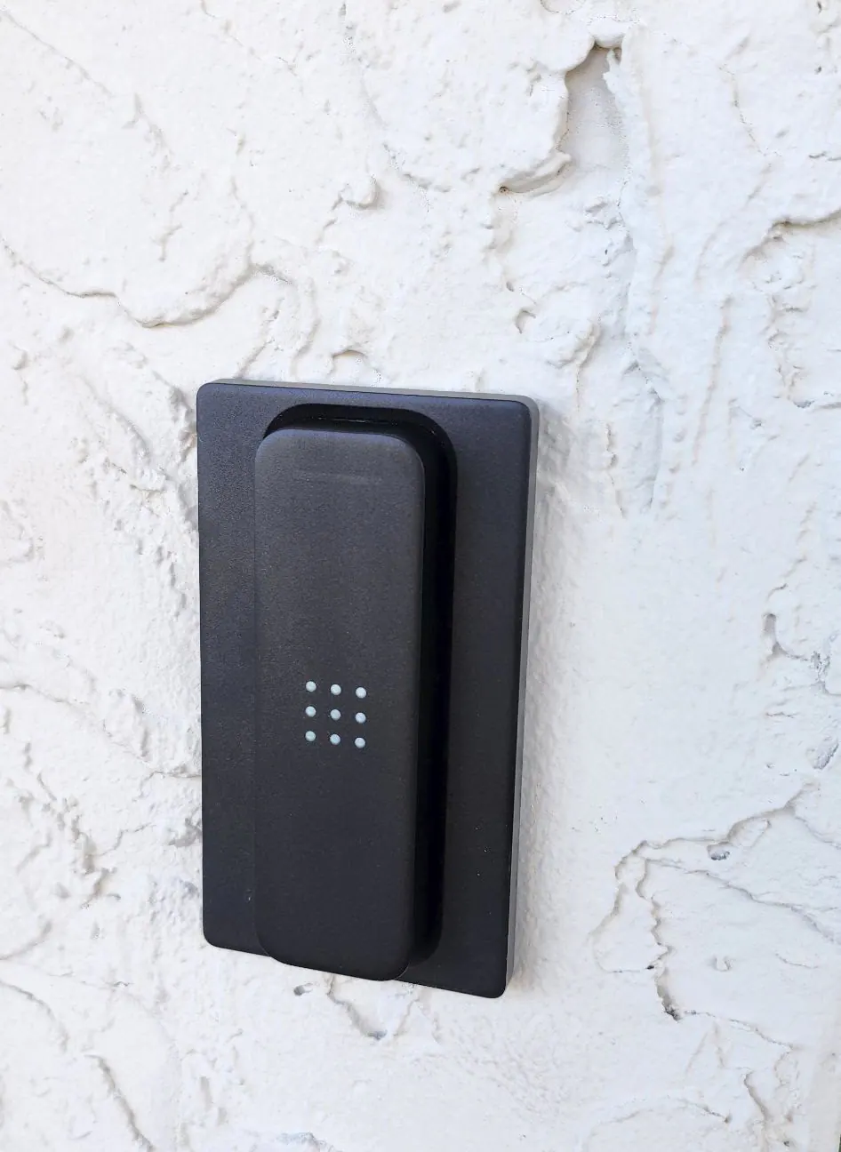 Black wall-mounted keypad reader on textured white stucco