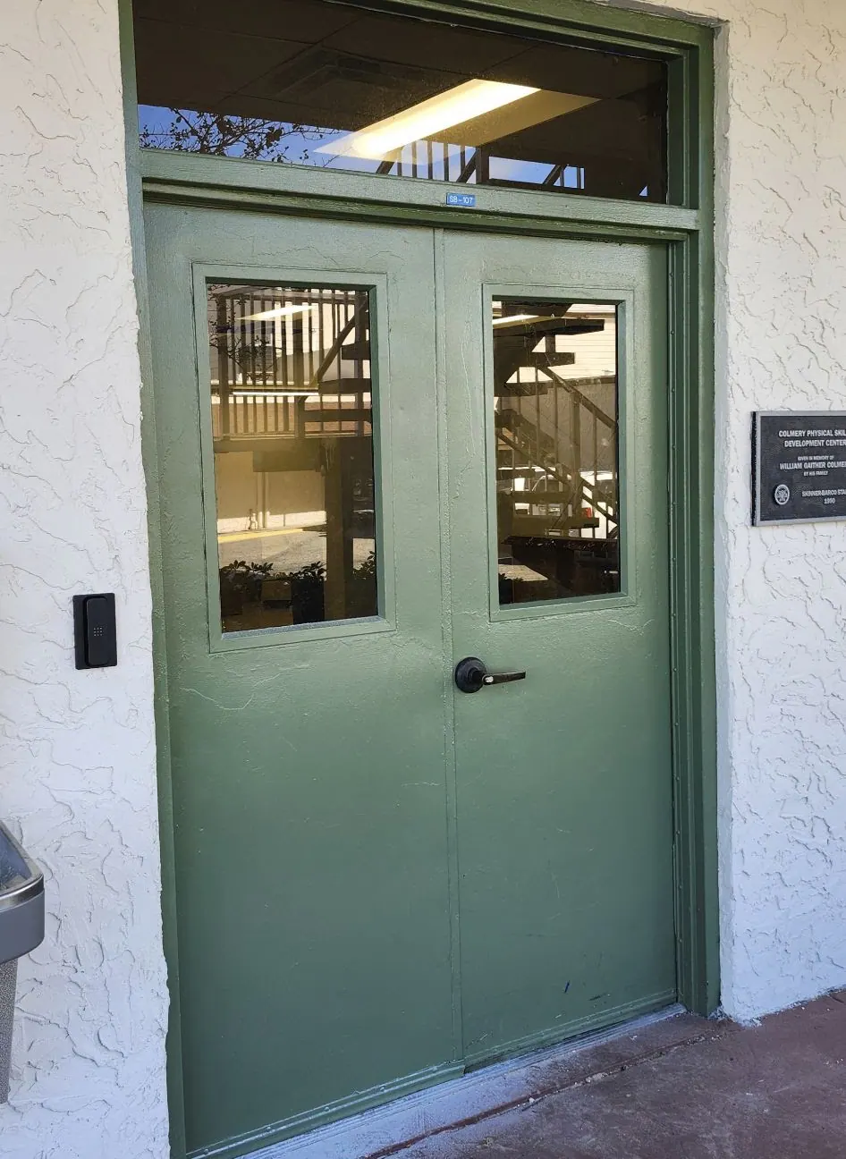 Green double doors with glass panels on a cream stucco entrance
