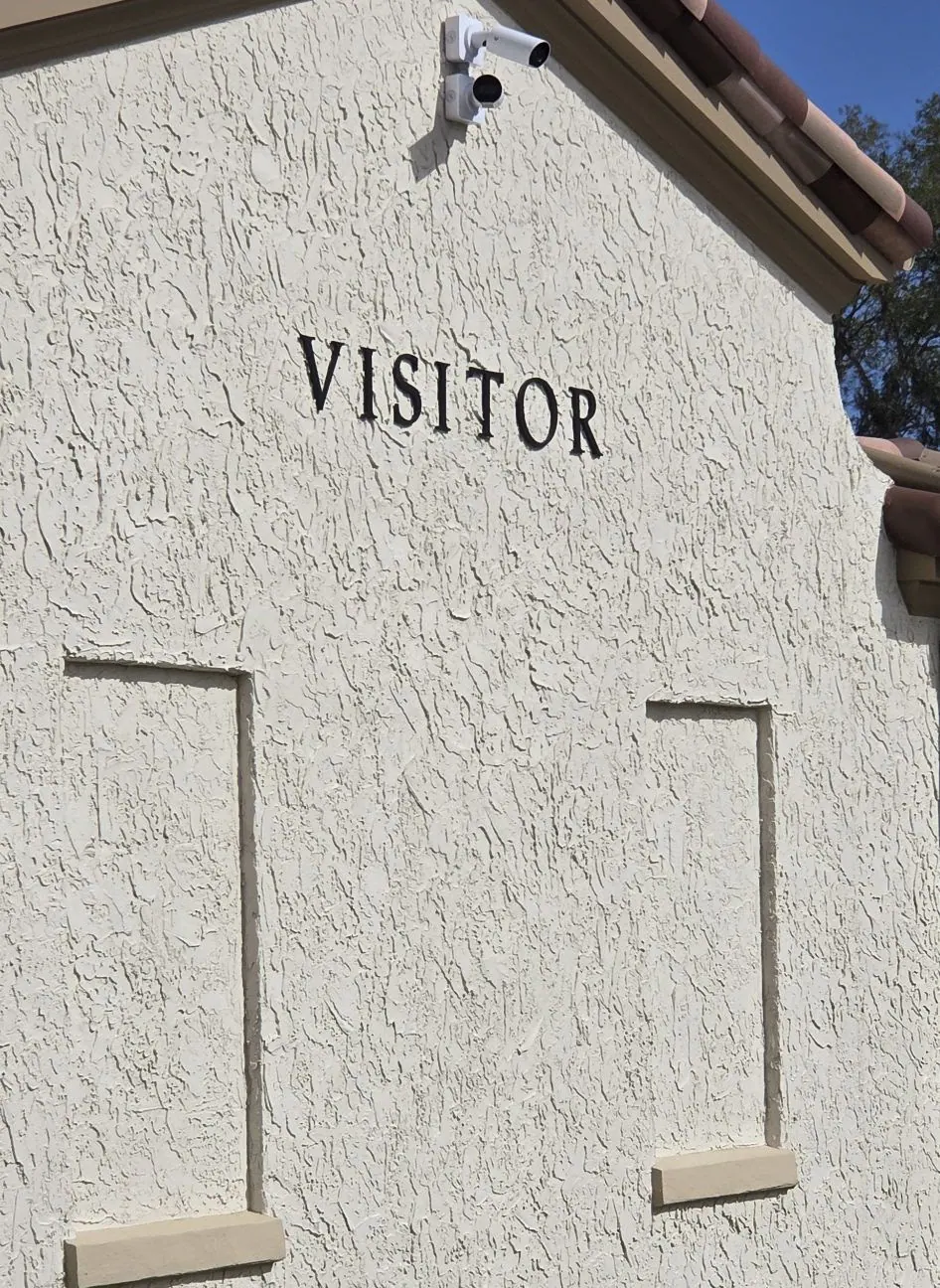 Stucco wall with the word VISITOR above a recessed panel