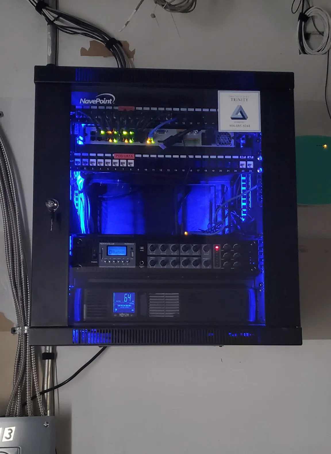 Wall-mounted black cabinet with a blue-lit amplifier and equipment