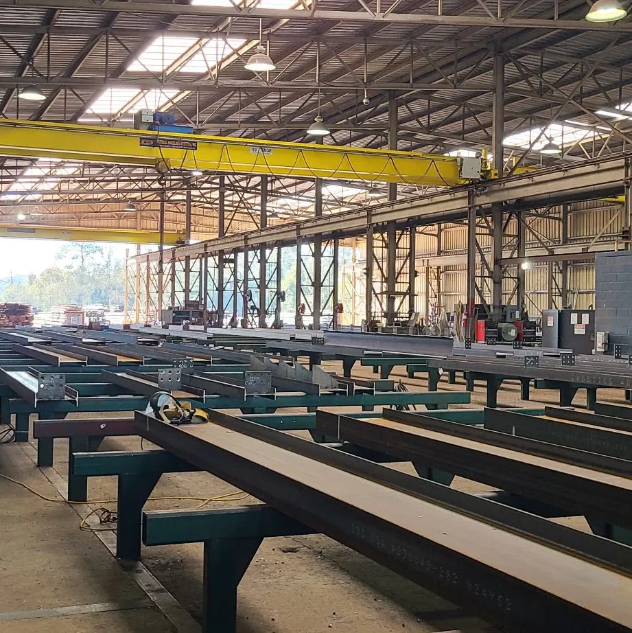 Steel shop with a yellow overhead crane above long steel beams