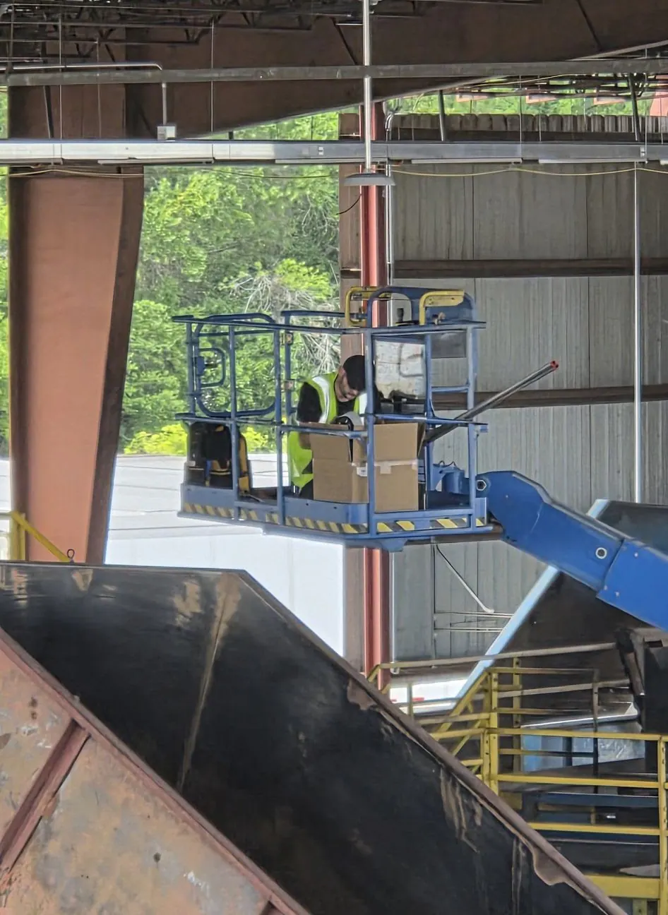 Boom lift and worker inside an industrial building with steel framing