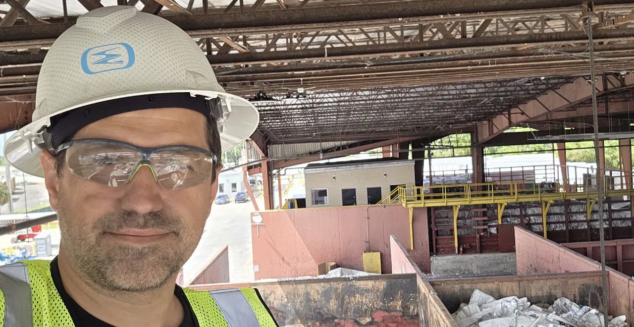 Worker in a white hard hat and safety glasses inside an industrial plant